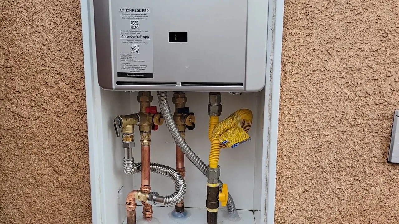 Wall-mounted tankless water heater in an exterior cabinet on a stucco wall with copper, gas and water lines below it.